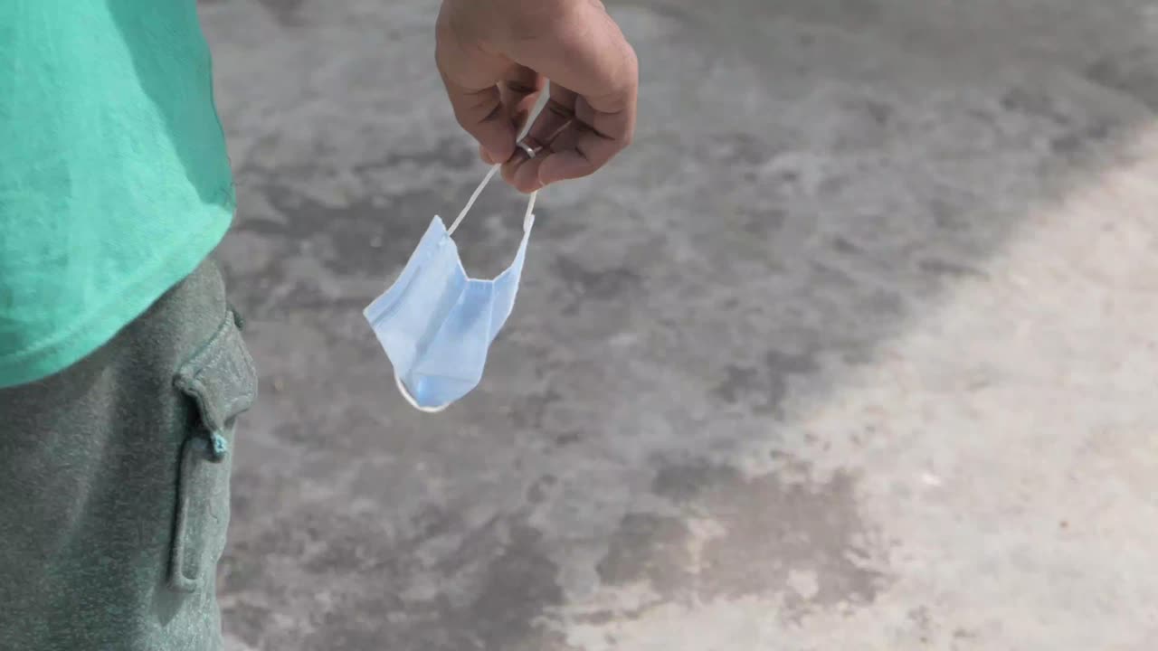 야외에서 사용된 얼굴 마스크를 들고 있는 사람