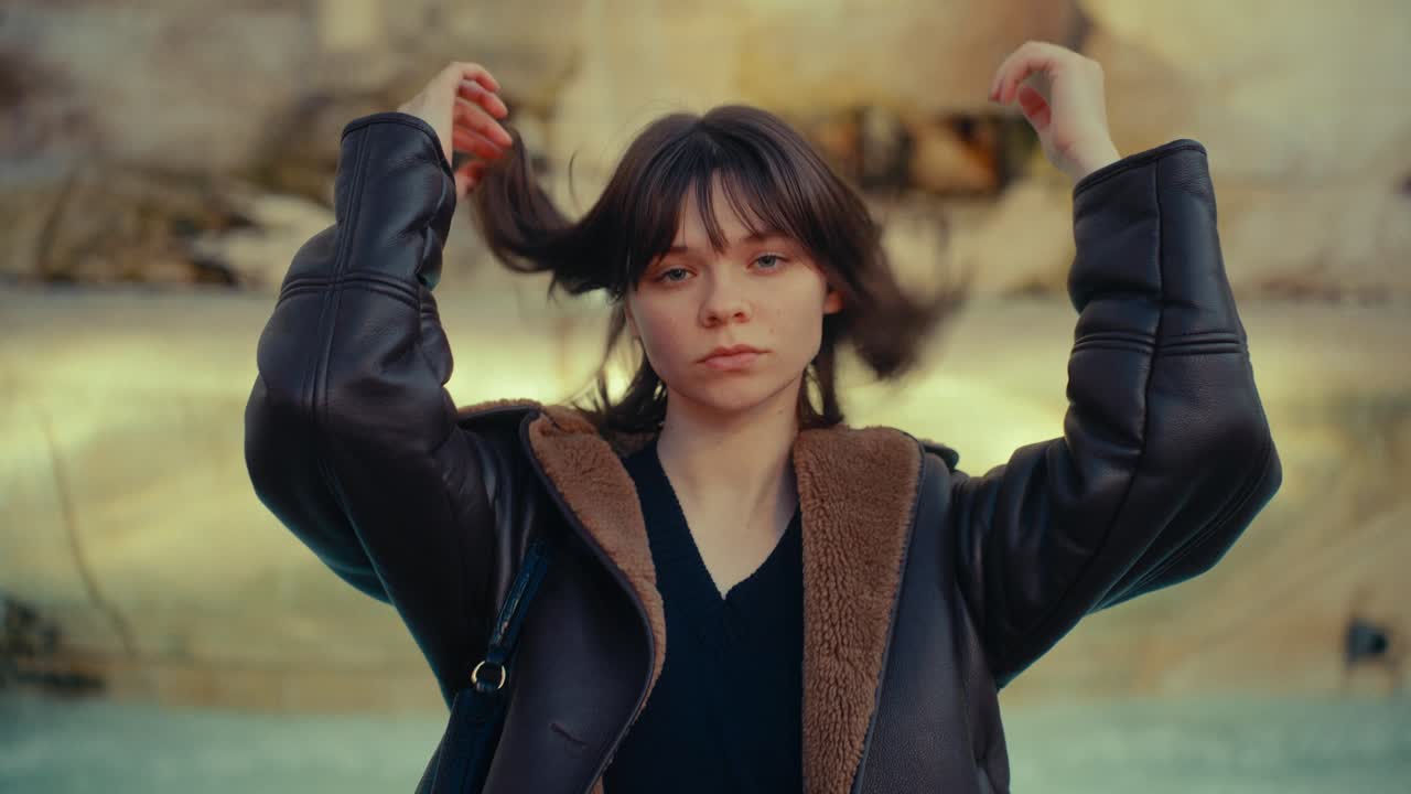 Jeune femme pensive qui s'ajuste les cheveux en extérieur