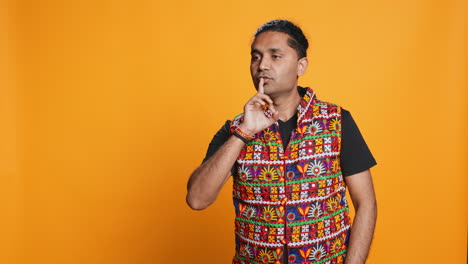 person placing finger on lips, doing quiet sign gesture, studio background