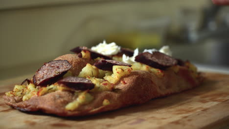chef componiendo una pizza: colocando mozzarella encima de una pizza estilo romano de patatas y salchichas