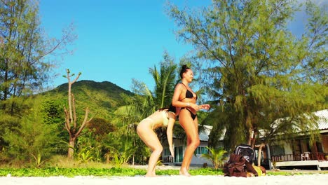 Beautiful-women-standing-on-exotic-beach-with-green-tropical-plants-background,-washing-with-sunscreen-their-bodies,-tanning-on-sunlight-of-Bali