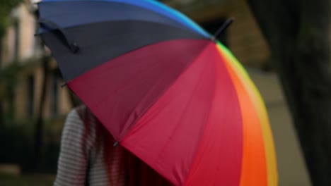 Nahaufnahme-Eines-Sich-Drehenden-Bunten-Regenbogenregenschirms-In-Weiblichen-Händen.-Zeitlupenaufnahme