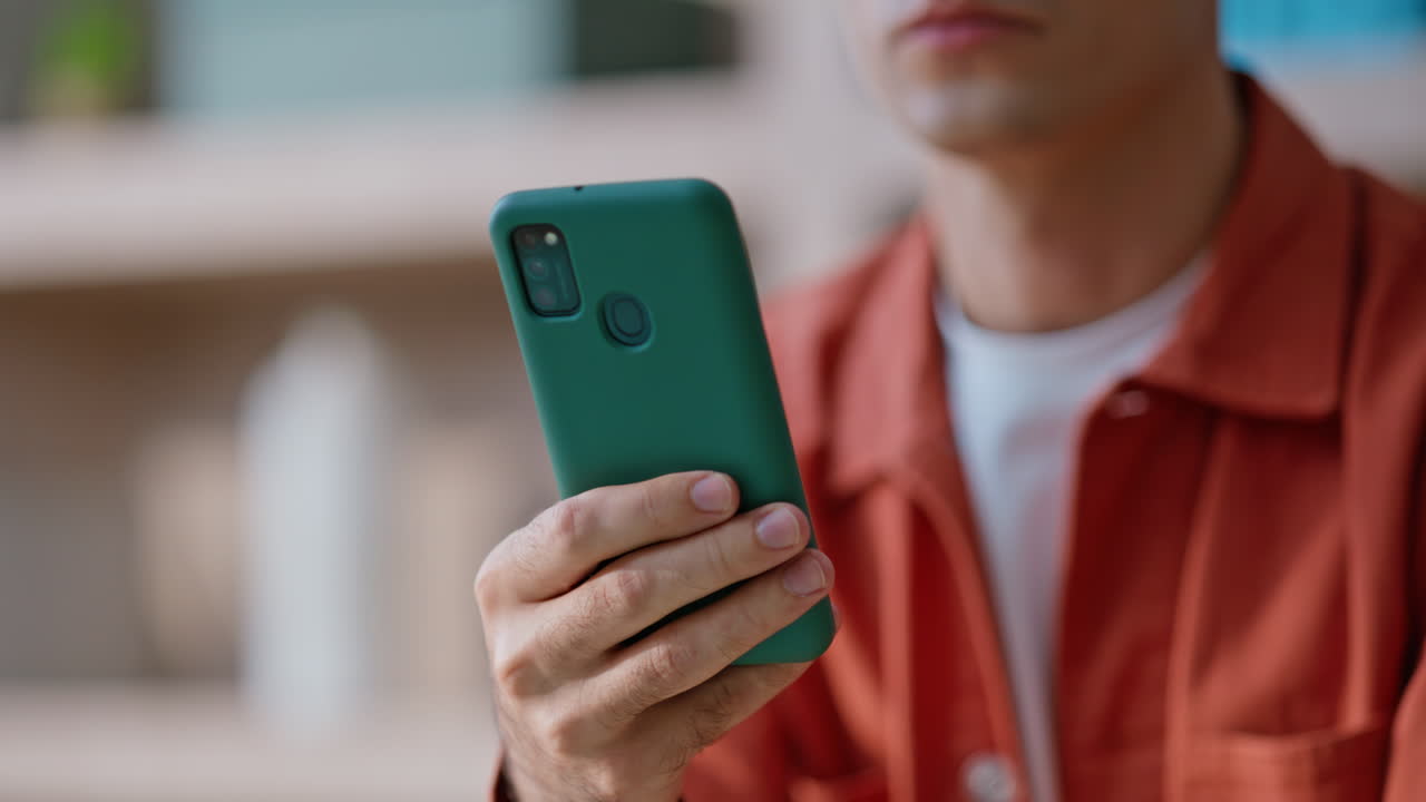 Student chatting online mobile phone sitting in apartment closeup. Man hand