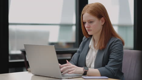 woman is working with laptop in office typing e-mail for partners and employees serious and successful businesswoman