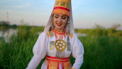 cute girl in folk costume of mari people is dancing outdoors