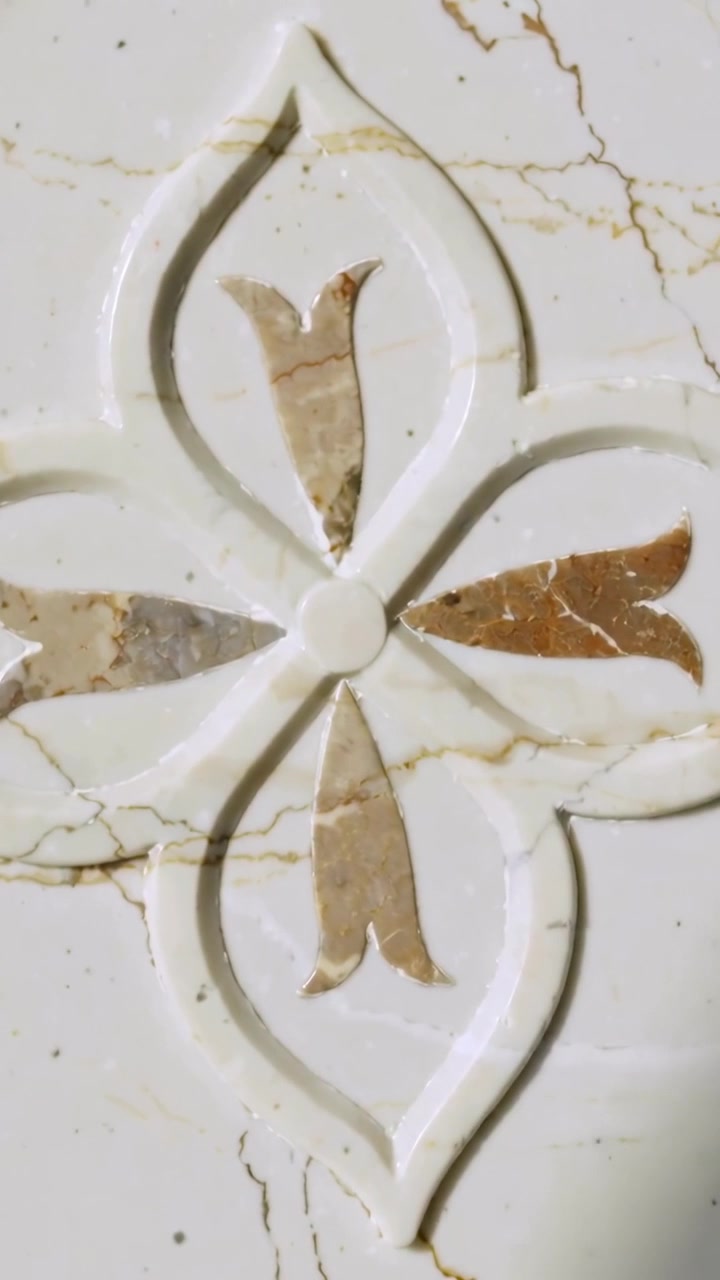 Vertikal video: Kamera begynder panorering over marmorpanel, afslører hævet blomstermotiv, beige indlæg.