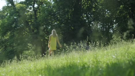 woman in yellow dress dancing by tree in summer park