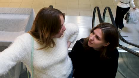 dos mujeres hablando en una escalera mecánica en un centro comercial