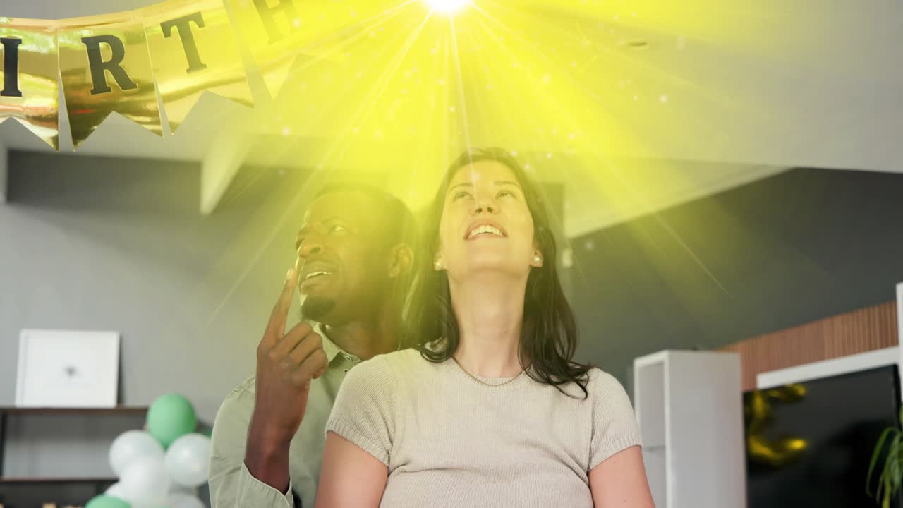 Man supporting woman holding teal balloon, yellow flare drawing them up during birthday