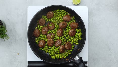 woman adding peanuts to meatballs with beans