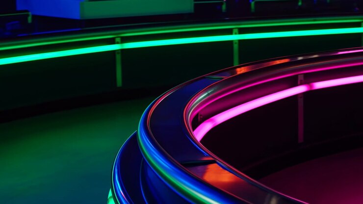 Un primo piano dal basso mostra binari metallici curvi e lucidi con strisce LED integrate magenta, verdi, blu e ciano all'interno di un interno scuro, creando forti riflessi, un bagliore saturo, profondità stratificata e.