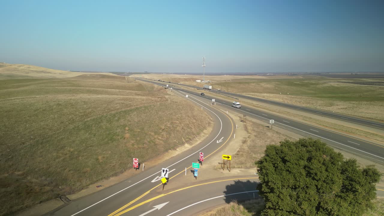 Aerial Drone view of Highway 5 near Newman reveals vast farmland, winding roads, and rural California's tranquil charm under a wide-open sky