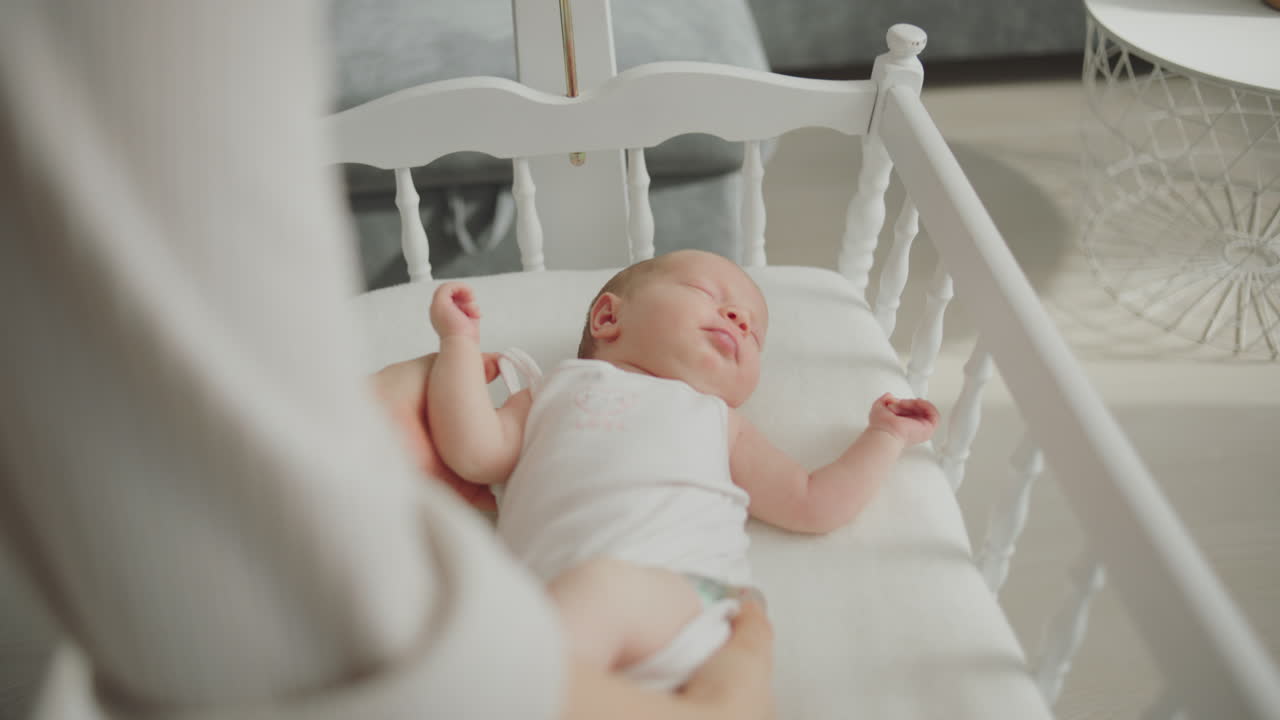 Madre che veglia dolcemente su un bambino addormentato in una culla bianca