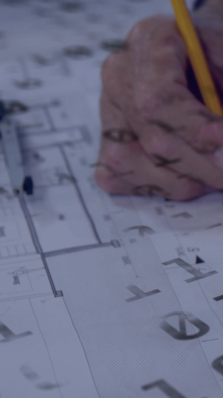 Vídeo vertical: Mão de arquiteto inserindo marcações em plantas com lápis amarelo usando compasso para revisão