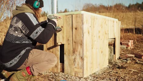 hombre construyendo una bañera de agua caliente cerrándola con tablas de madera