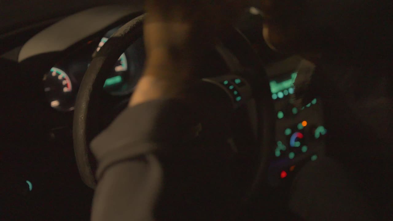 차의 운전석에 앉아 있는 흑인 남자가 분노와 좌절으로 스티어링  ⁇ 을 때리고 있습니다.