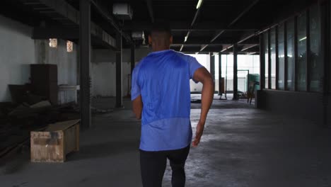 african american man wearing sports clothing jogging through an empty urban building