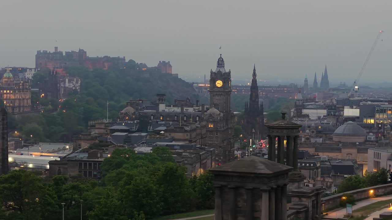 Cinematisk droneoptagelse af Edinburgh på en tåget eftermiddag med det historiske slot i baggrunden. Stemningsfuld atmosfære, blødt lys og ikonisk skyline.