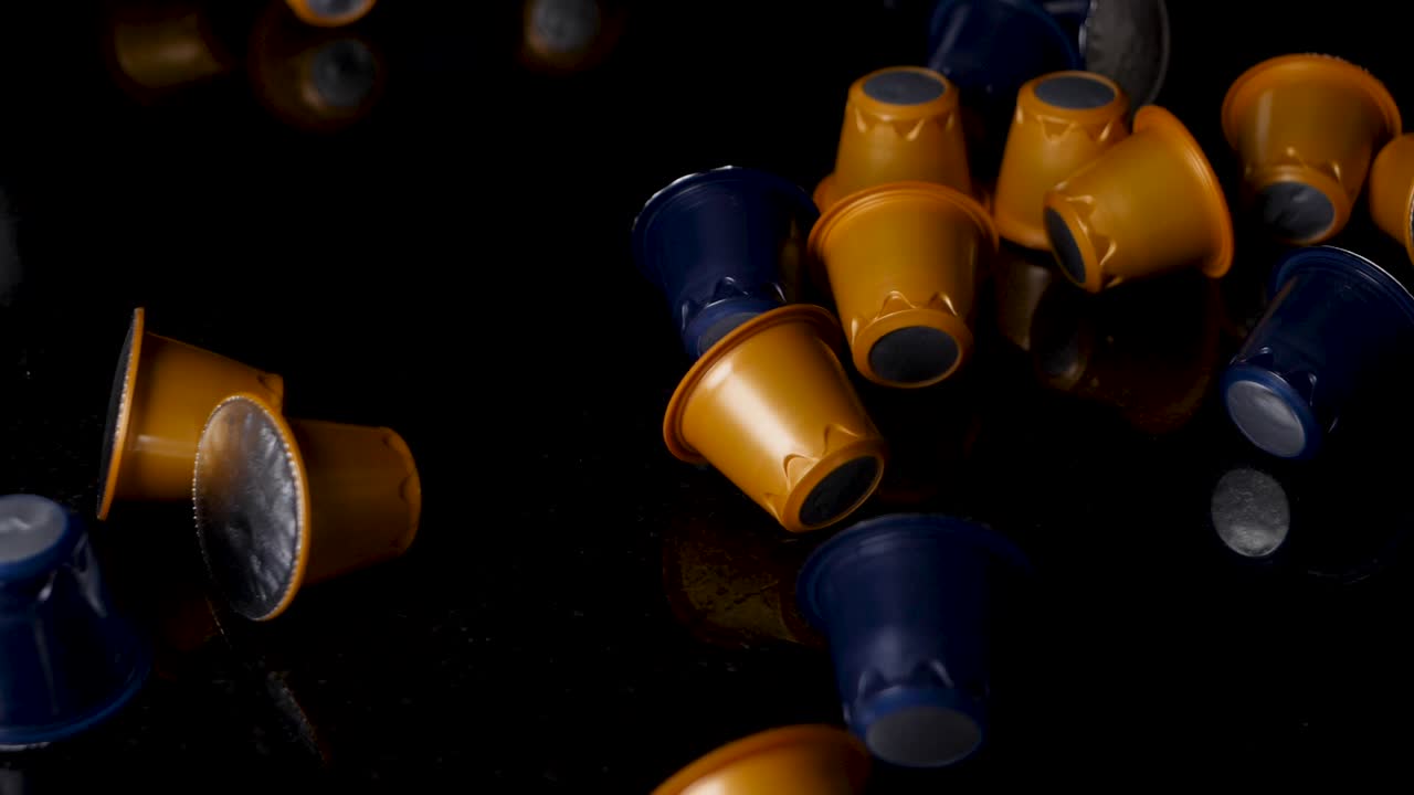 Variety of coffee pods blue and yellow color fall on black surface