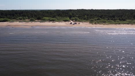 A-breathtaking-drone-view-of-the-Baltic-Sea-coastline,-showcasing-the-expansive-sandy-beaches,-and-adjacent-lush-green-forests