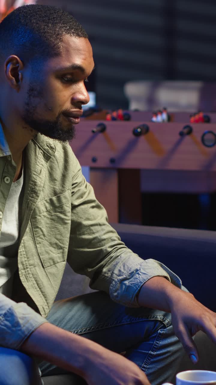 Vertical Video Young black guy working on his freelance tasks in the living room