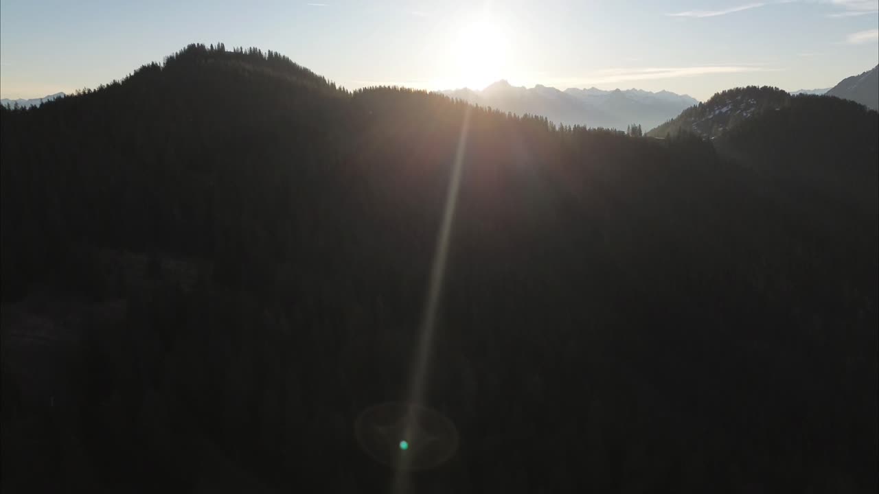 drone vuela hacia el amanecer sobre el bosque rodeado de un hermoso paisaje montañoso, bludenz, austria, europa
