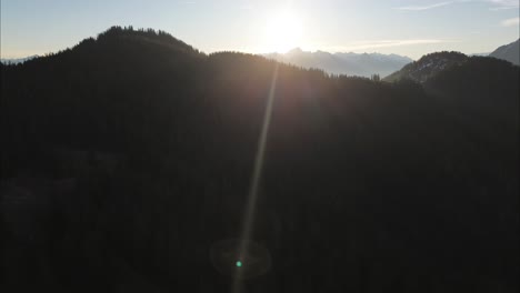 Drone-fly-towards-Sunrise-above-Forest-surrounded-by-Beautiful-Mountain-Landscape,-Bludenz,-Austria,-Europe