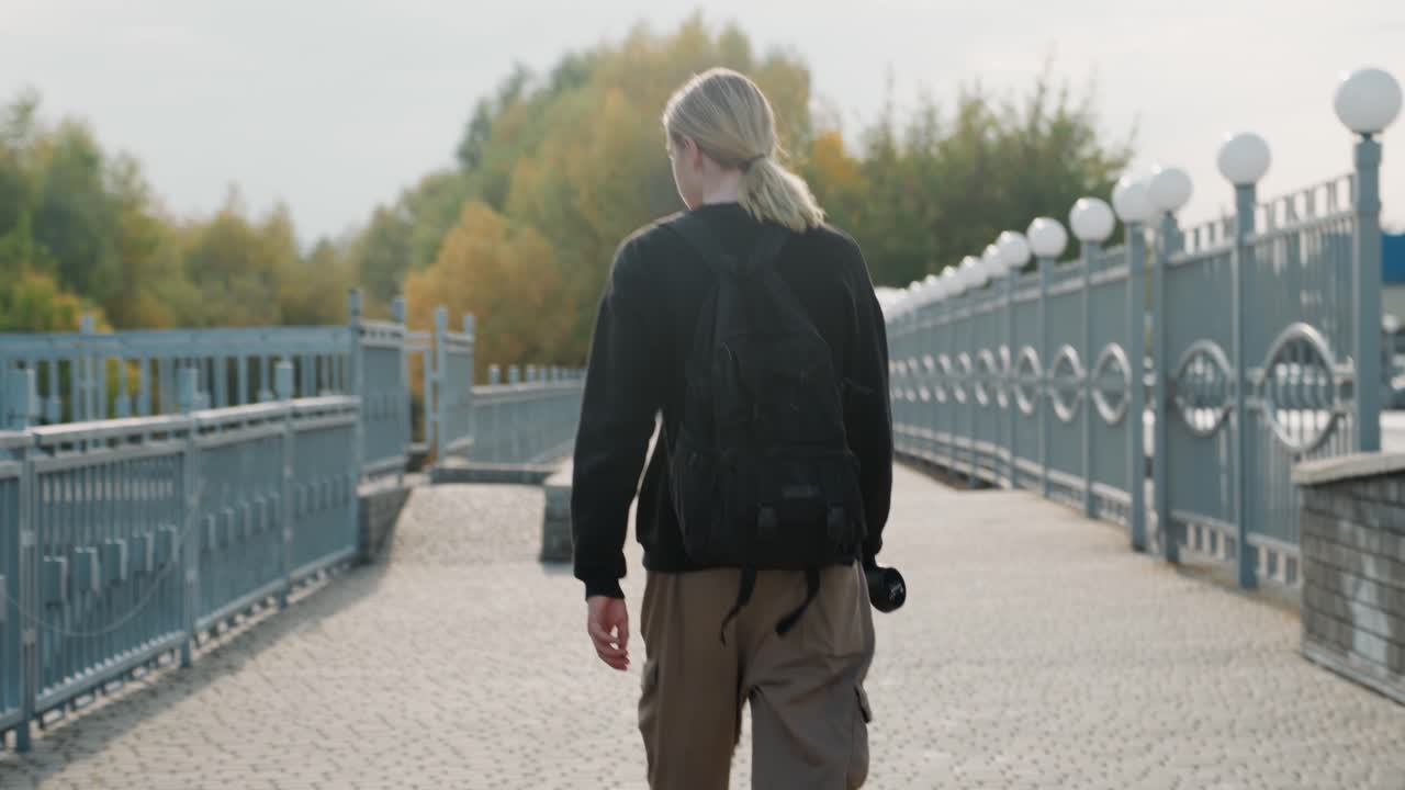Photographer trekking through cityscape. Filmmaker exploring city with equipment in hand. Individual capturing city scenes and autumn charm with steady steps and equipment in urban environment