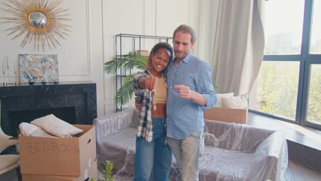 diverse family of woman and man rejoices in moving and shows keys to apartment