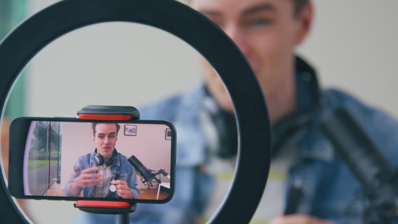 Vlogger uomo in diretta streaming un video di recensione di un orologio da polso da casa, registrato dal cellulare.
