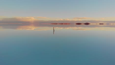 Aerial of a lone figure standing on the mirrored reflection of the world&#039;s largest salt flat in the Uyuni Salt Flats , Bolivia