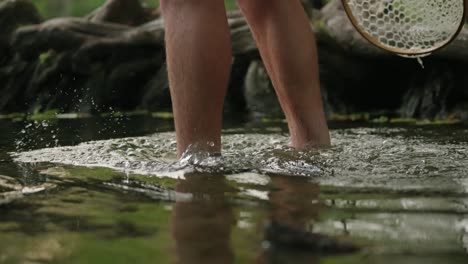 flyfisherman wading into beautiful green swimming hole splashing in river walking in water to go fishing with fall foliage in slow motion 4k close up