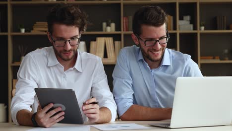 los jóvenes hermanos gemelos se sientan en el escritorio usando una tableta portátil