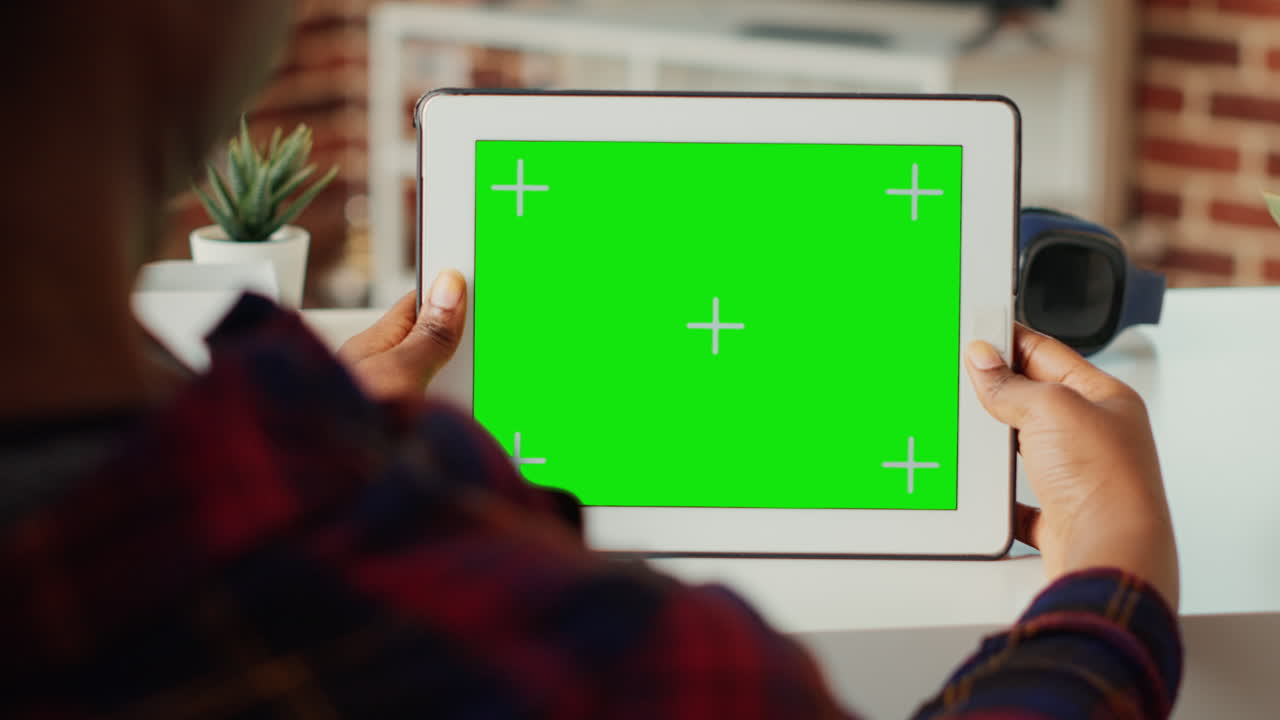 Female freelancer holding digital gadget with horizontal green screen