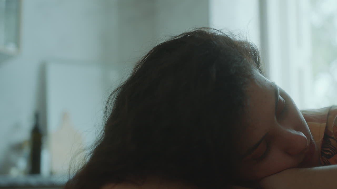 테이블에 기대어, 사려 깊게 주위를 둘러보는 젊은 내성적인 소녀