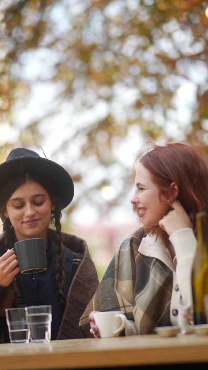 두 여인이 가을에 야외에서 커피를 즐기고 있다
