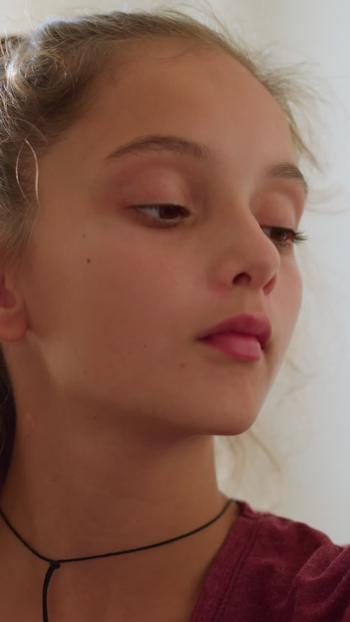 Cute girl looking thoughtfully at someone in the background, soft light illuminating her face, indoor setting with gentle atmosphere, concerned or curious expression, calm moment