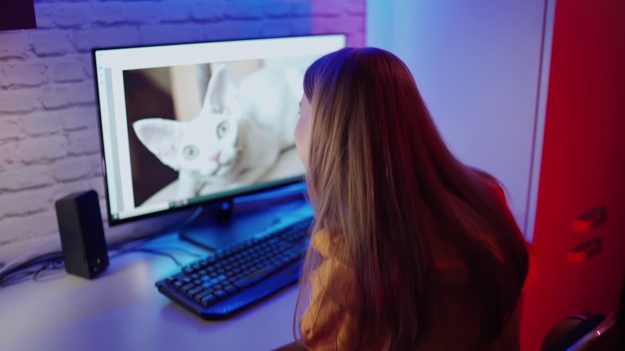 Girl using computer in her house. Rear view of happy young woman using computer