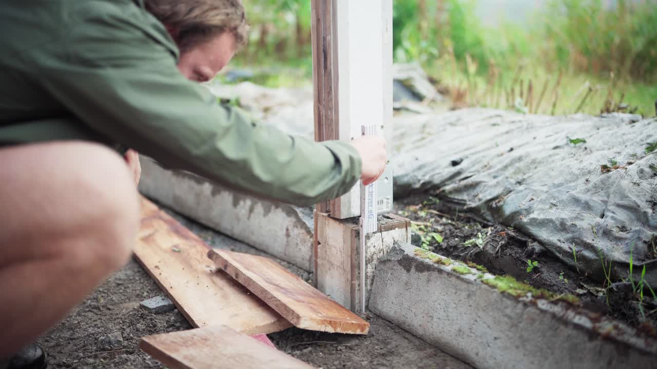 Un uomo prende le misure del palo per la costruzione di una serra - Primo piano
