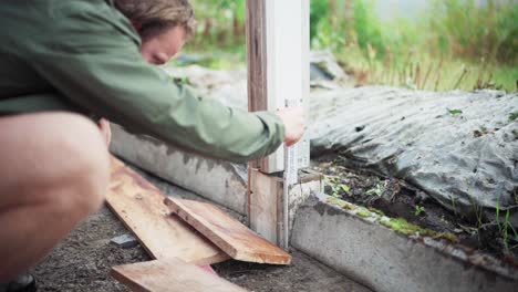 A Man is Taking Measurements of the Post for the Construction of a Greenhouse - Close Up