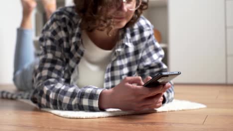 girl schoolboy studen lies on the floor with a phone in her hands. hands holding a modern