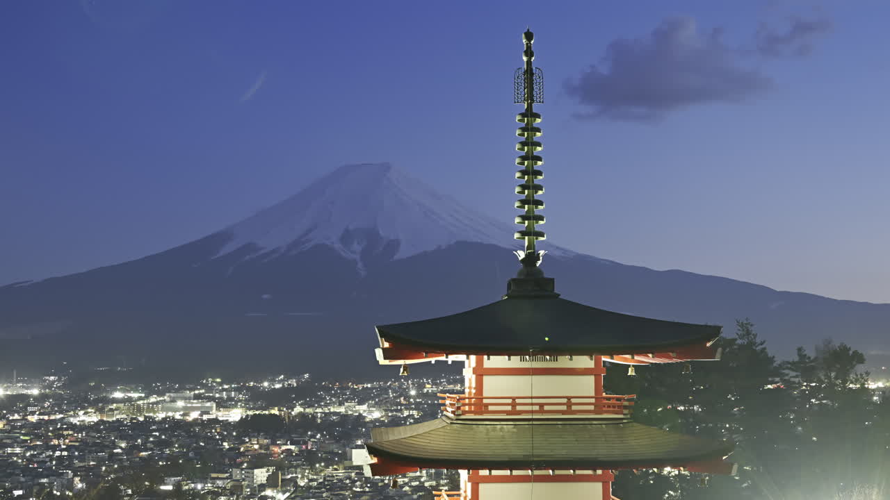 Chureito Pagoda timelapse at twilight sunset, overlooking a sprawling Fujikawaguchiko city as the sun sets behind majestic Fuji mountain