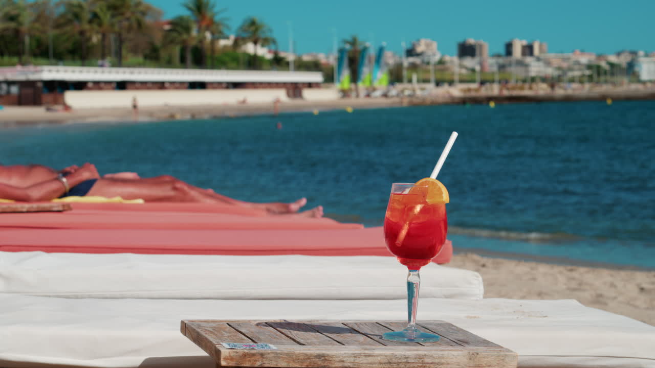 Close up of a refreshing red orange cocktail with orange slice and ice cubes, captured outdoors on a sunny day in Cannes