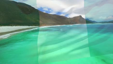 Digital-composition-of-waving-nigeria-flag-against-aerial-view-of-beach-and-sea-waves