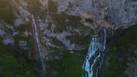 aerial-view-of-the-wild-cascades-nestled-within-the-Nivica-Canyon,-surrounded-by-karst-cliffs-and-inviting-pools