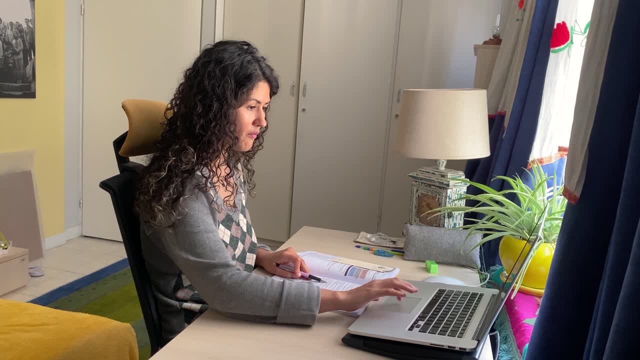 Mujer trabajando en Irán, usando un portátil en casa, con ropa de vestir negra, en una habitación con diseño minimalista y decoración de colores arquitectónicos, trabajando desde casa, tomando un curso en línea en Teherán, en una habitación cerrada, escribiendo y aprendiendo.