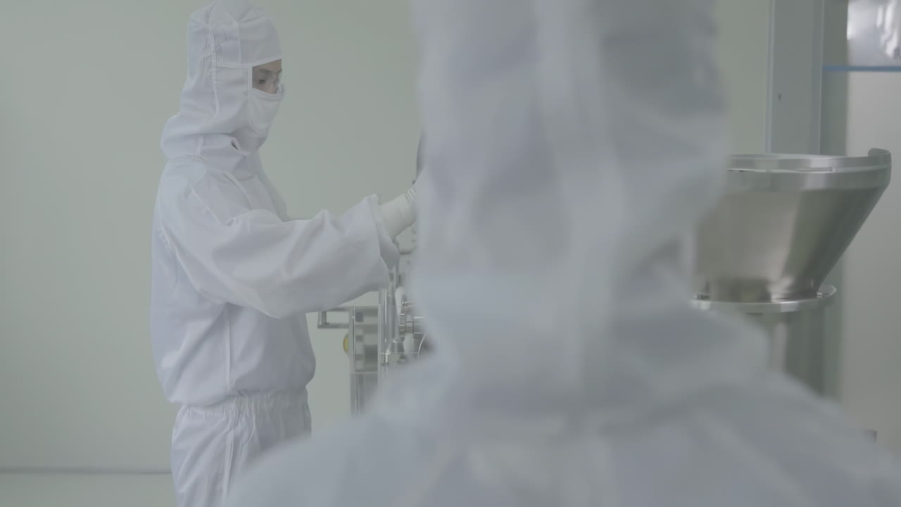 Scientists or workers in lab coats and masks are conducting quality control for medication vials, ensuring the safety and efficacy of the products being manufactured at Sterile pharmaceutical factory