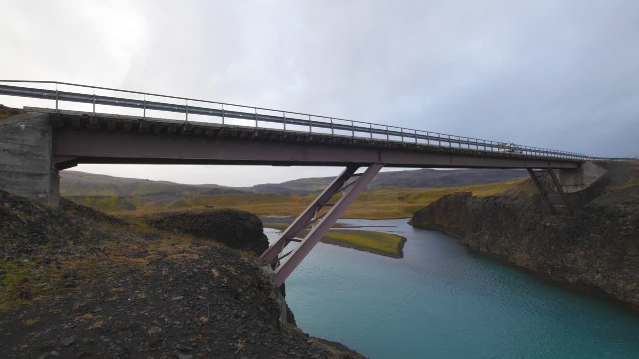 автомобиль пересекает розовый мост в исландии. облачный день