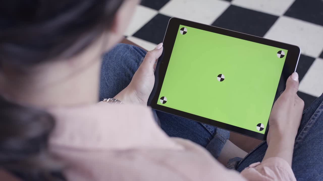 녹색 화면을 가진 태블릿을 사용하는 여성