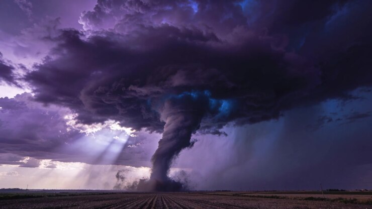 Tightening wall cloud spawning tornado, intensifying over field, lofting dust, sunbeams, rain